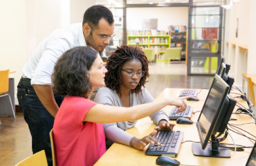 Students And Teacher Looking At Computer